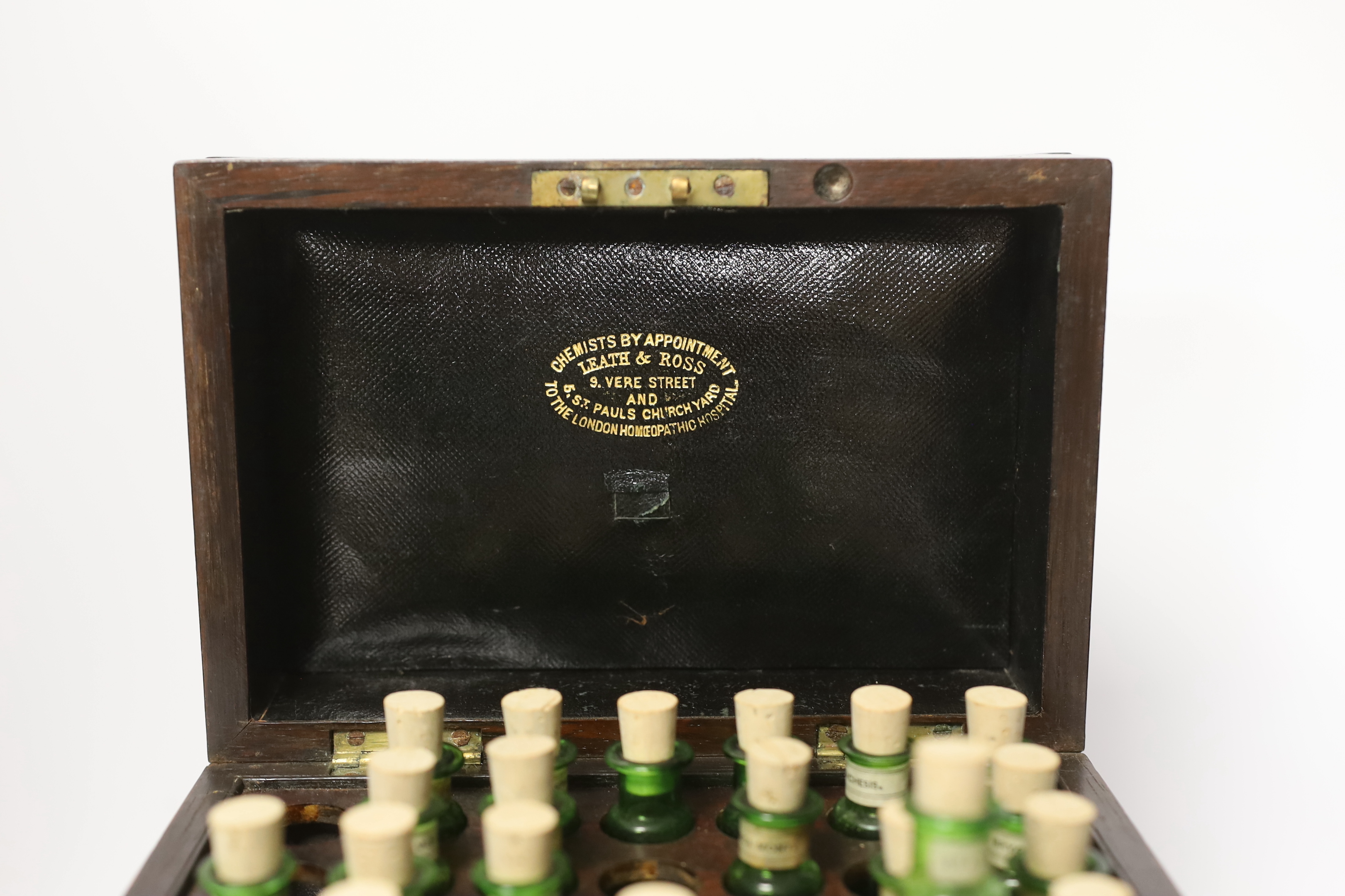 A Victorian rosewood homeopathic apothecary box, by Leath and Ross, two segmented drawers below a top opening section, containing a number of labelled chemists bottles, 21cm high, 20cm wide, 13.5cm deep
